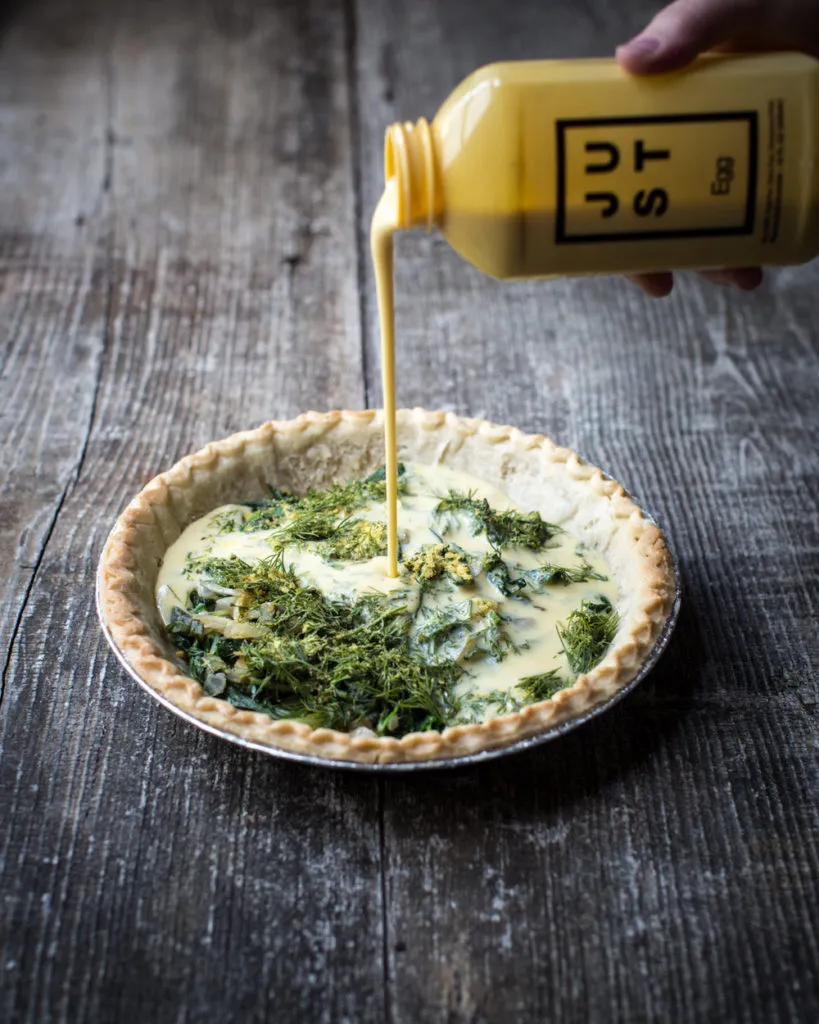 Flüssige JUST Egg-Mischung wird in einen vorgebackenen Quicheboden mit verschiedenen Füllungen gegossen.