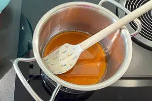 Flüssiger Honig und Pflanzenöl werden in einem kleinen Topf langsam erwärmt, um das Granola zu binden.