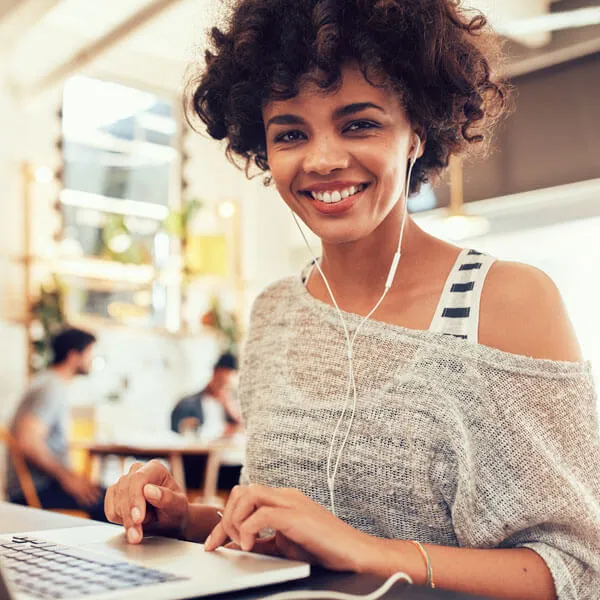 Frau mit In-Ear-Kopfhörern vor Laptop beim Online Lernen für eine Online Marketing Fortbildung