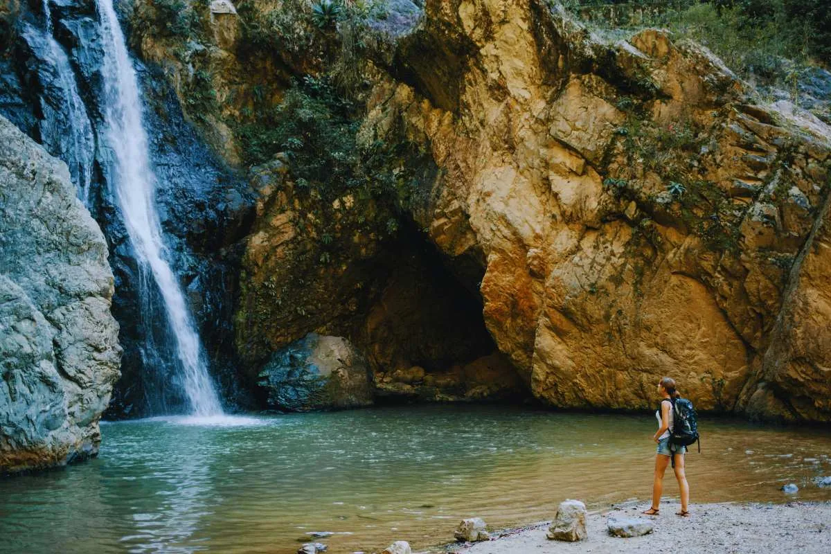 Frau spaziert an einem Wasserfall