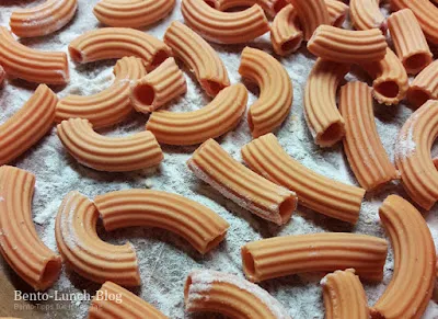 Frisch extrudierte glutenfreie Linsennudeln aus dem Pastamaker, bereit zum Kochen.