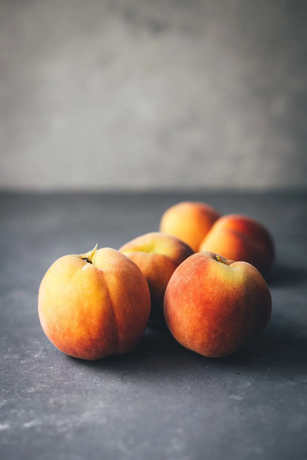 Frisch geerntete, reife Pfirsiche in einer Schüssel, teilweise geschnitten, bereit für die Zubereitung des Pfirsichkuchens.