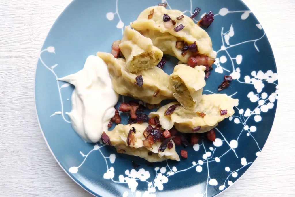 Frisch gekochte Wareniki, ukrainische Teigtaschen mit einer Füllung aus Kartoffeln und Schalotten, garniert mit frischen Kräutern.