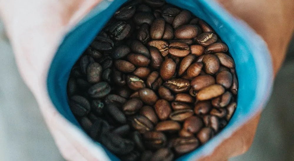 Frisch geröstete Kaffeebohnen in einer Packung, bereit für die mobile Kaffeezubereitung auf Reisen.