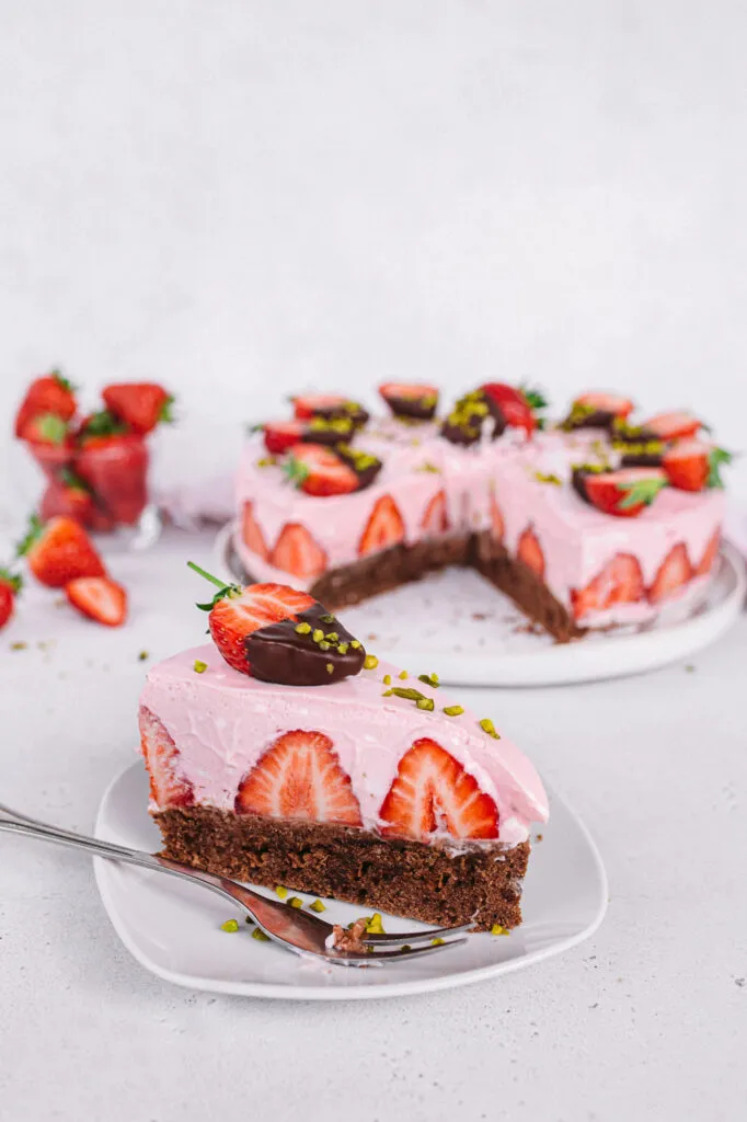 Frisch zubereitete vegane Erdbeer-Sahne-Torte mit Schokoladenboden und reichlich Erdbeeren, fertig zum Anschneiden