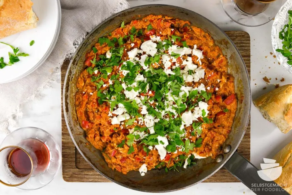 Frisch zubereitetes Menemen, ein beliebtes türkisches Frühstück, serviert in der Pfanne mit Feta und Brot