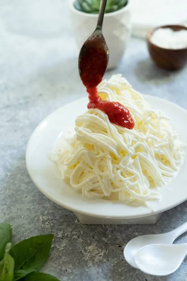 Frisch zubereitetes Spaghettieis mit Erdbeersauce und weißer Schokolade