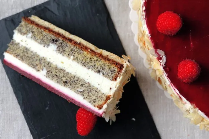 Frische Himbeer-Mohn Sahnetorte, garniert mit frischen Himbeeren und Mohnsamen, als perfekter deutscher Kaffeekuchen.