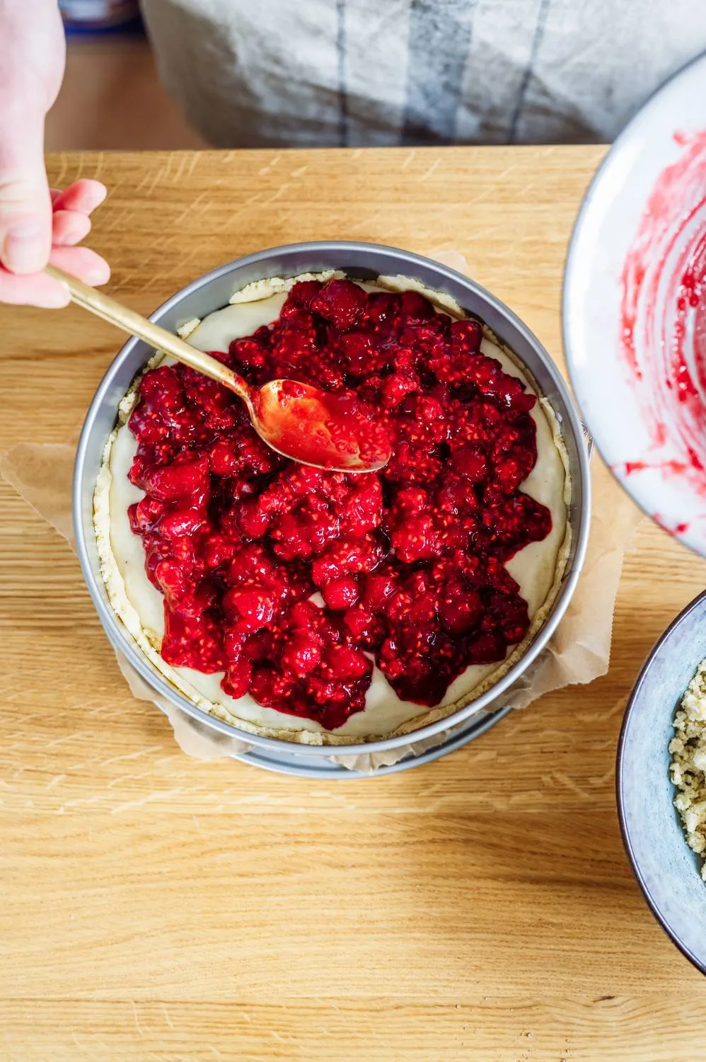 Frische Himbeeren vorsichtig mit Himbeermarmelade vermengt für die fruchtige Schicht des Geburtstagskuchens