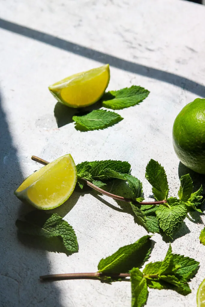 Frische Limetten und eine Minze auf einem Schneidebrett, bereit für die Zubereitung einer erfrischenden Bowle