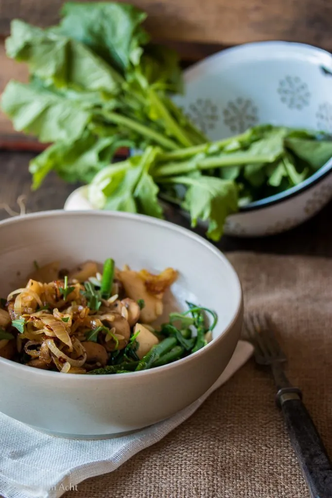 Frische Orzo-Nudeln mit Mairübchen, Pilzen und grünem Spargel in einer eleganten Schale, servierfertig