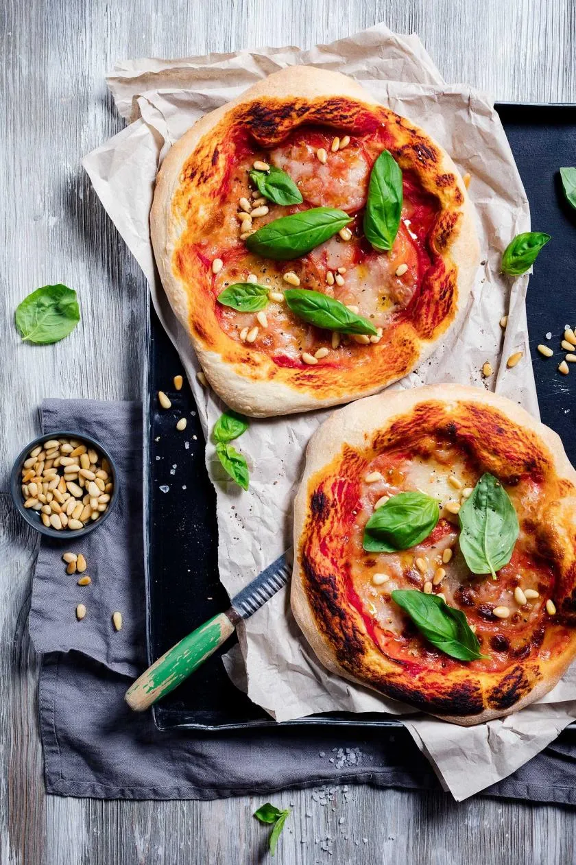 Frische Pizza Caprese mit Scheiben von Mozzarella, reifen Tomaten und Basilikumblättern auf Tomatensauce.
