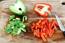 Frische rote und grüne Paprika werden für den griechischen Bauernsalat geschnitten.