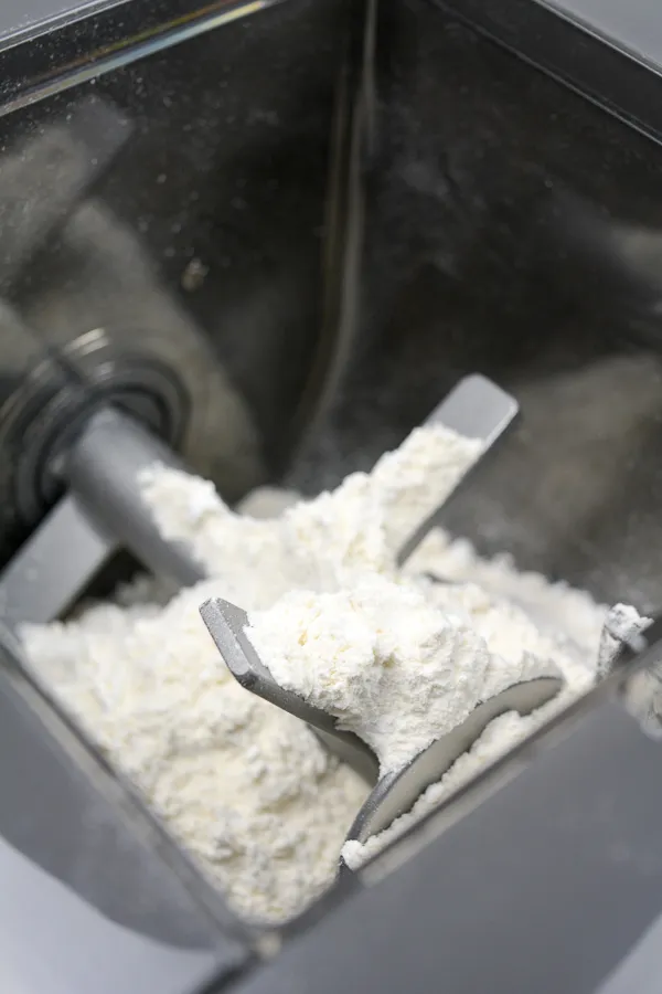 Frische Spritzgebäck-Rohlinge in verschiedenen Formen, bereit zum Backen auf einem mit Backpapier ausgelegten Blech
