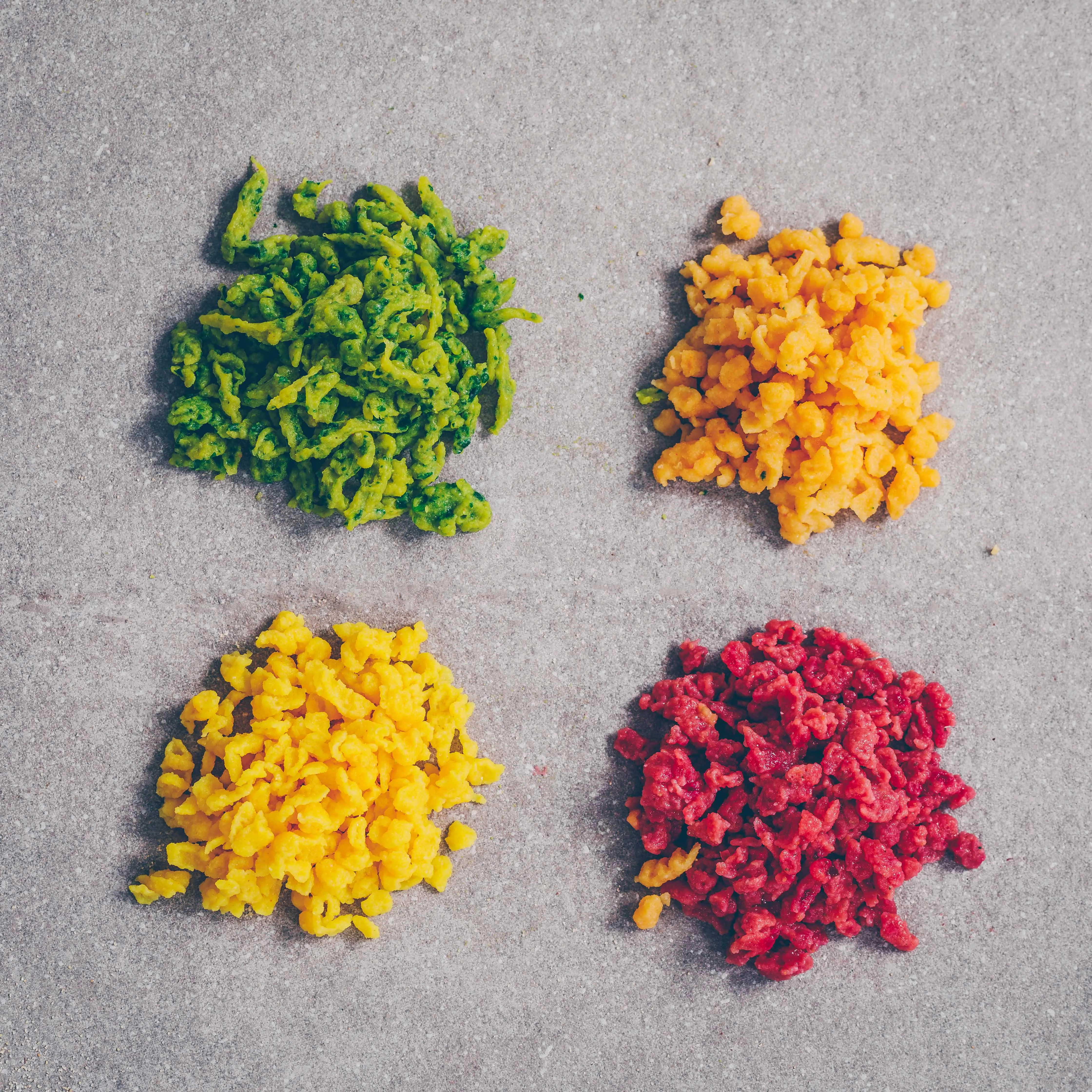 Frische vegane Knöpfli werden mit einem Spätzle-Blech und Schieber direkt in kochendes Wasser geschabt.