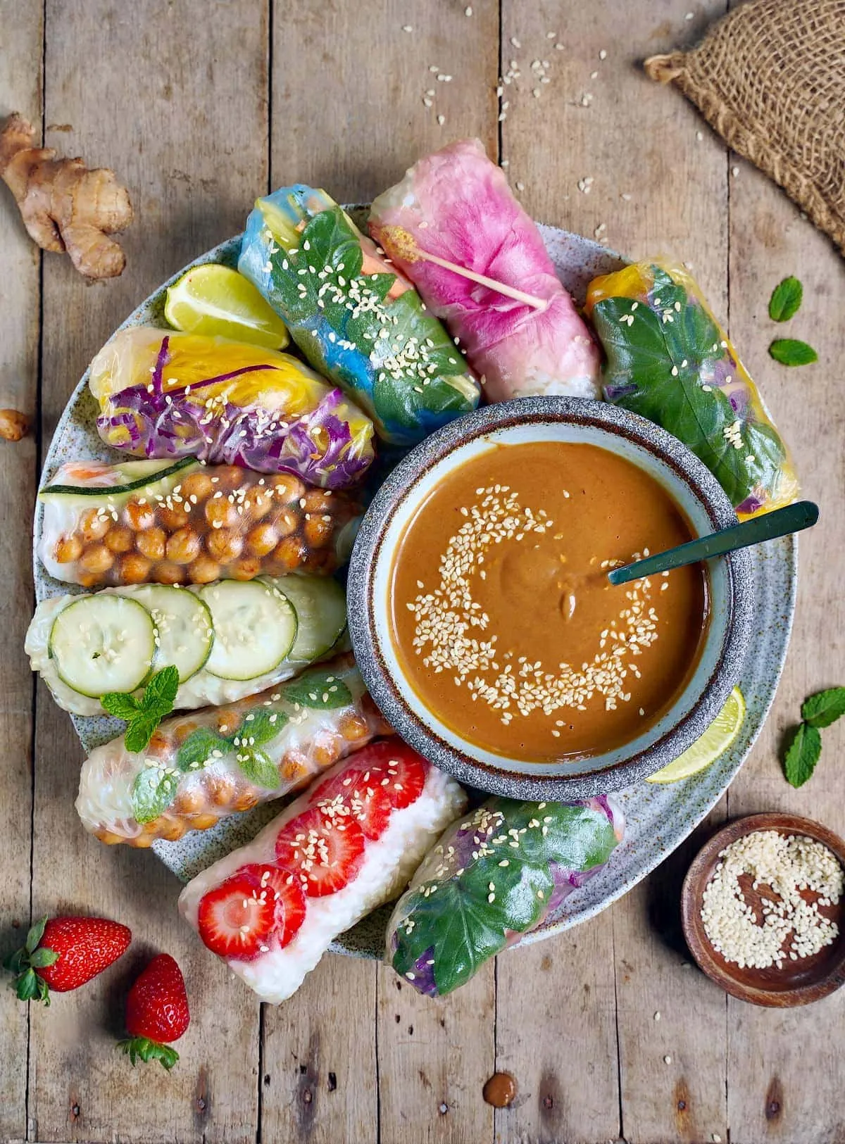 Frische vegane Sommerrollen mit vielfältigen Gemüsefüllungen und cremiger Erdnusssauce auf einem großen Teller, ein gesundes Mittagessen.