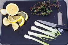 Frische Zitronenscheiben, angedrückter Knoblauch und Thymianzweige werden für die mediterrane Soße des Zitronen-Lachses vorbereitet.