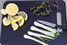 Frische Zitronenscheiben, aromatische Thymianzweige und angedrückter Knoblauch als Beigabe für Lachs im Backofen.