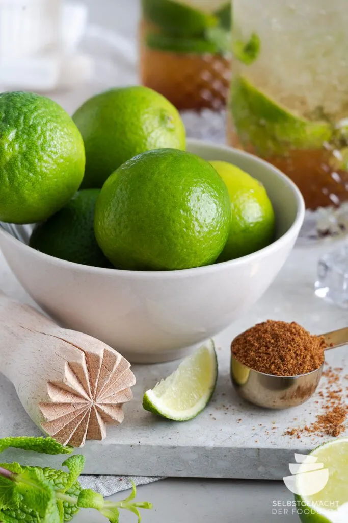 Frische Zutaten für einen Virgin Mojito: Limetten, Minze, Zucker und Crushed Ice