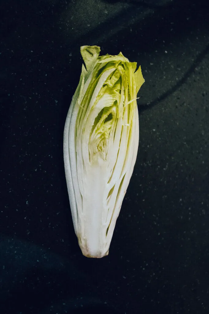 Frischer Chicoree auf einem Schneidebrett, vorbereitet für den gesunden Auflauf.