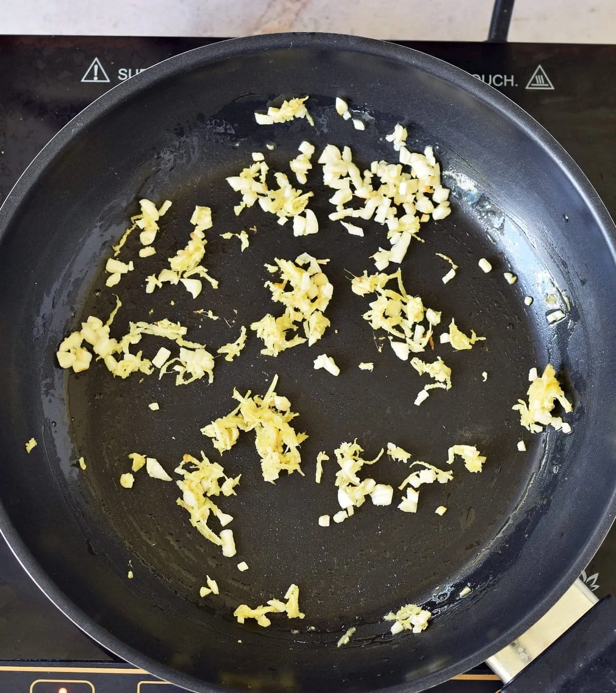 Frischer Ingwer und Knoblauch angebraten in schwarzer Pfanne