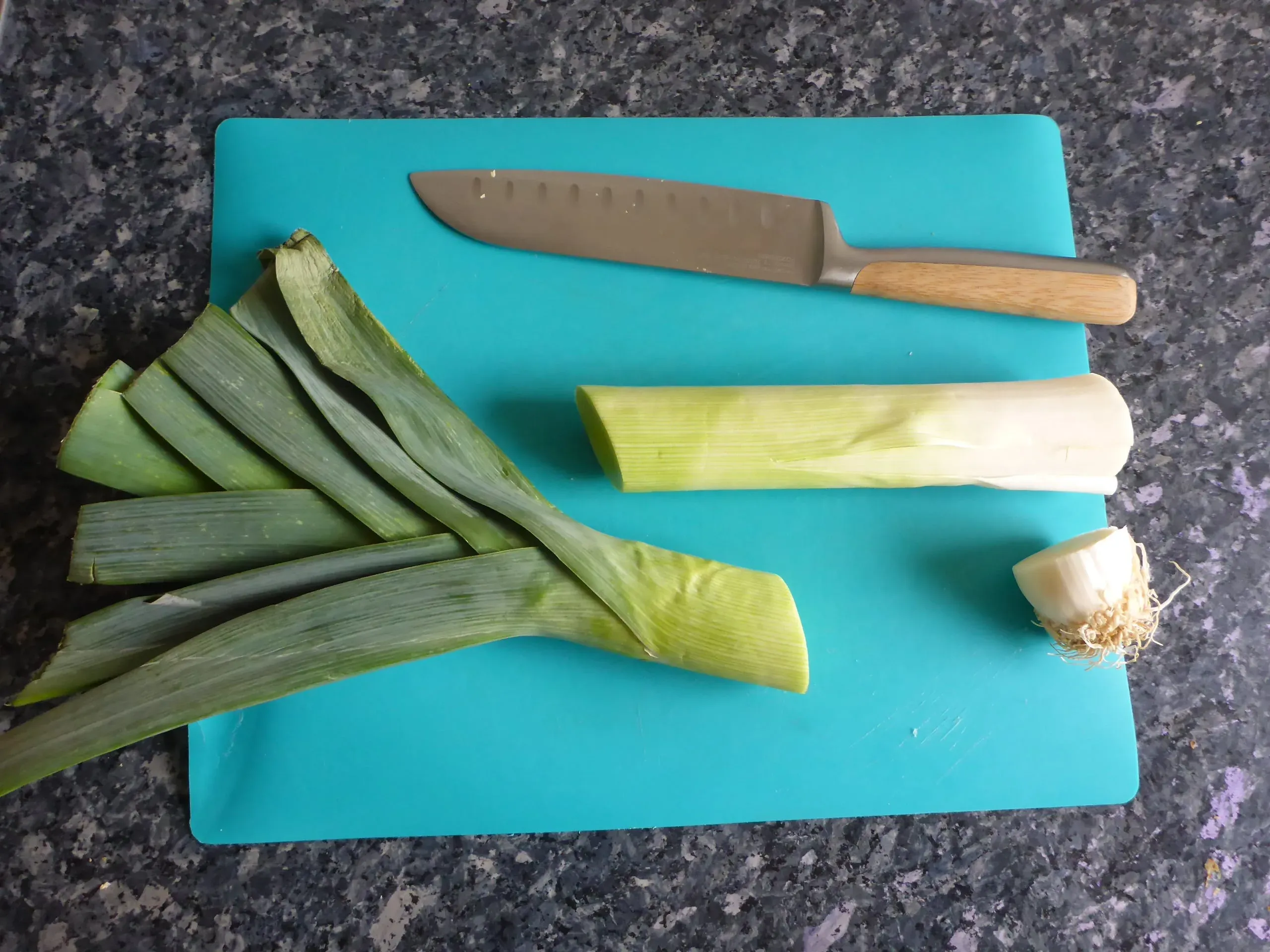 Frischer Lauch, der der Länge nach halbiert wurde, um ihn gründlich zu reinigen und auf die Zubereitung für die cremige Schnitzelpfanne vorzubereiten.