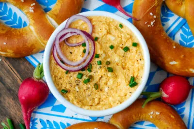 Frischer Obazda auf einer Holzplatte mit Brezn und Radieschen, perfekt für die bayerische Brotzeit
