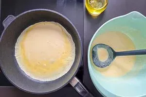 Frischer Pfannkuchenteig wird in einer beschichteten Pfanne mit heißem Öl goldbraun gebraten.