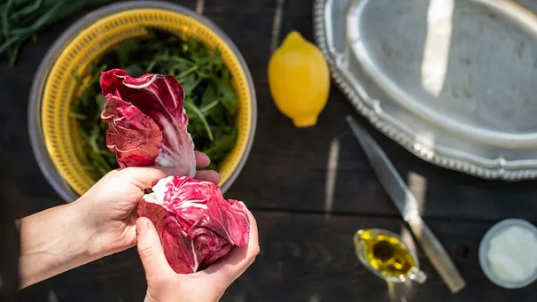 Frischer Radicchio und weitere Zutaten für einen bitterstoffreichen Salat auf einem Holztisch