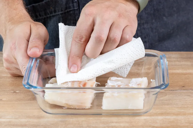 Frisches Kabeljaufilet sorgfältig mit Küchenpapier abtupfen, um es auf das Braten vorzubereiten.