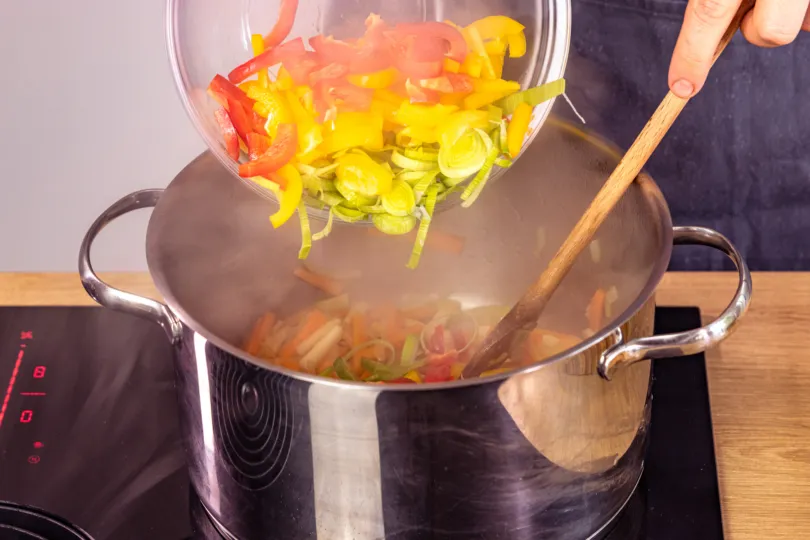 Frisches Suppengrün und Paprika werden in einem Topf angebraten für die Soljanka
