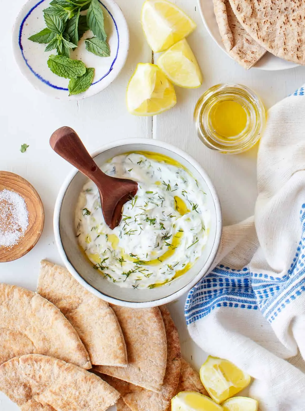 Frisches Tzatziki in einer Schale, garniert mit frischer Minze und Olivenöl, bereit zum Servieren mit Fladenbrot.
