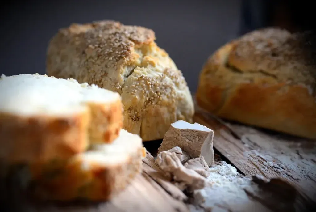 Frischhefe Würfel auf Holz mit Mehl und Brot – essenziell für handwerkliche Backkunst