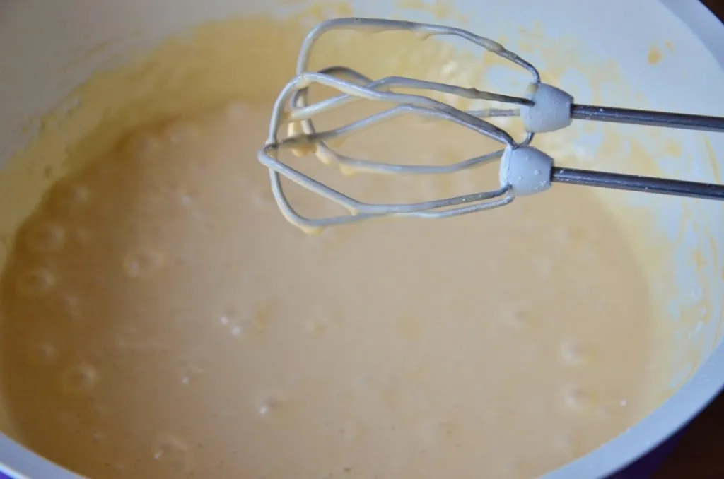 Frischkäse-Topping wird in einer Rührschüssel mit einem Löffel glatt gerührt, bereit für die Weiterverarbeitung