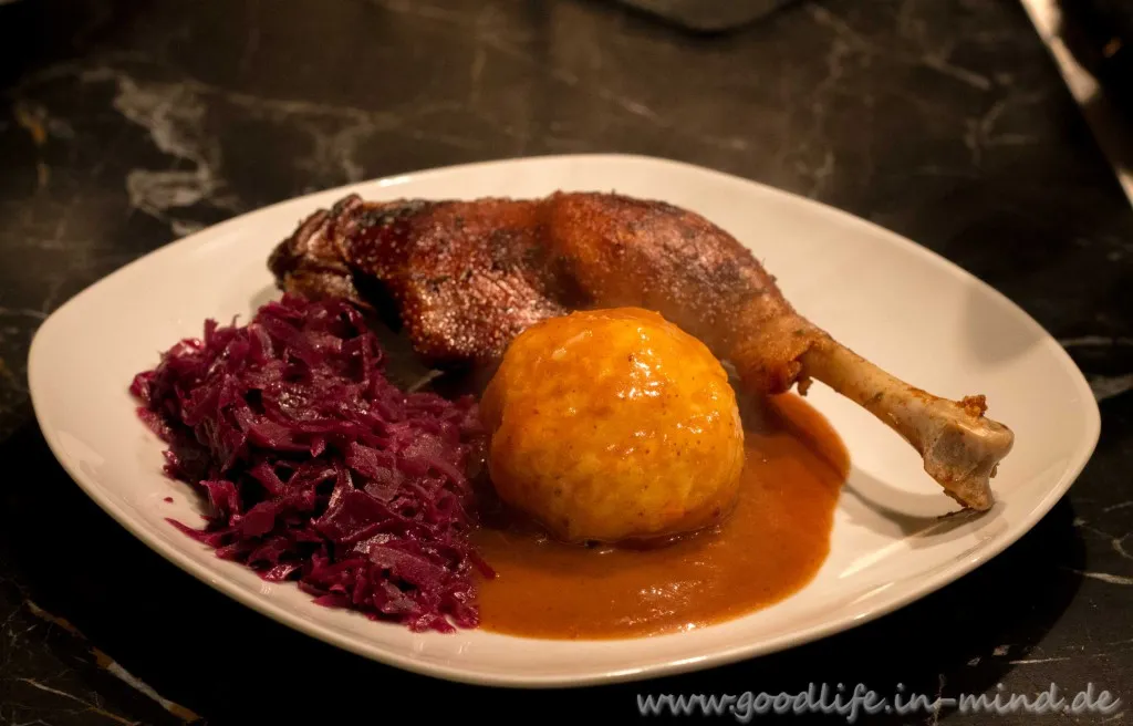 Gänsekeulen Niedriggarmethode mit Apfelspalten, Orangenscheiben, Cranberries, Backpflaumen, Schalotten und Thymianzweigen auf der Fettpfanne