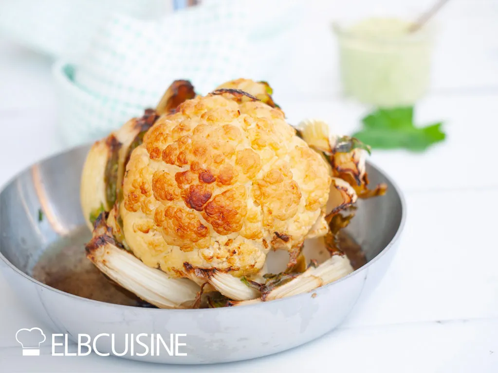 Ganzer gerösteter Blumenkohl nach Ottolenghi in einer Ofenform, bereit zum Servieren