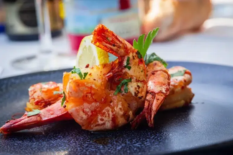 Gebratene Garnele mit Schale und Kräutern auf einem rustikalen Teller, servierfertig.