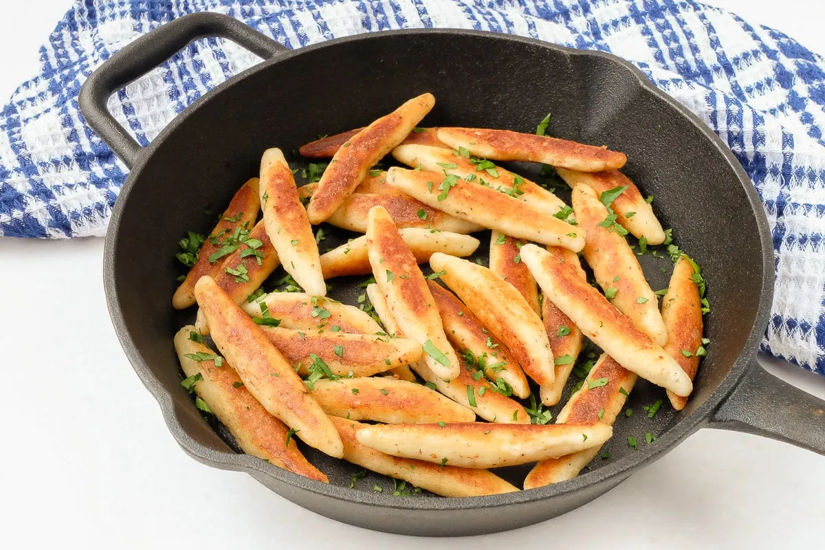 gebratene Schupfnudeln mit Petersilie in einer gusseisernen Pfanne