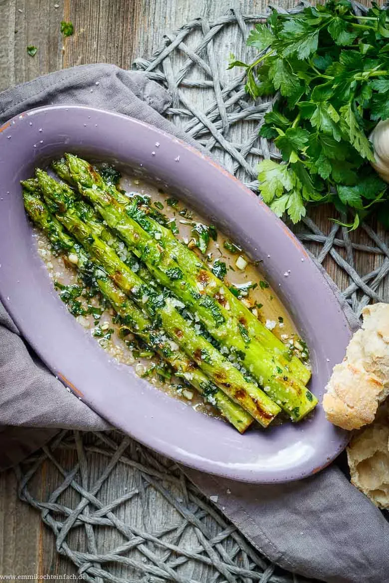 Gebratener grüner Spargel in der Pfanne, reich verziert mit frischen Kräutern und Gewürzen