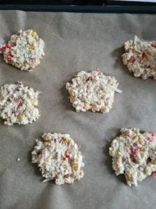 Geformte körniger Frischkäse Taler auf Backpapier, bereit zum Backen im Ofen.