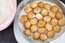 Gefrorene Windbeutel auf dem Tortenboden mit etwas Creme, Start der schnellen Windbeuteltorte.