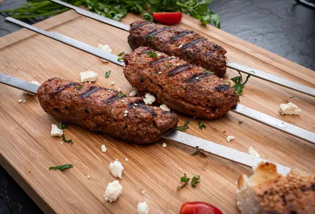 Gefüllte Köfte Spieße angerichtet auf einem Holzbrett