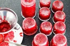 Gefüllte Marmeladengläser stehen auf dem Kopf, um ein Vakuum zu bilden und die Himbeermarmelade sicher zu konservieren.