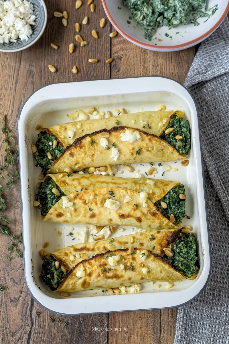 Gefüllte Pfannkuchen mit Spinat, Ricotta und Feta, appetitlich angerichtet in einer Auflaufform