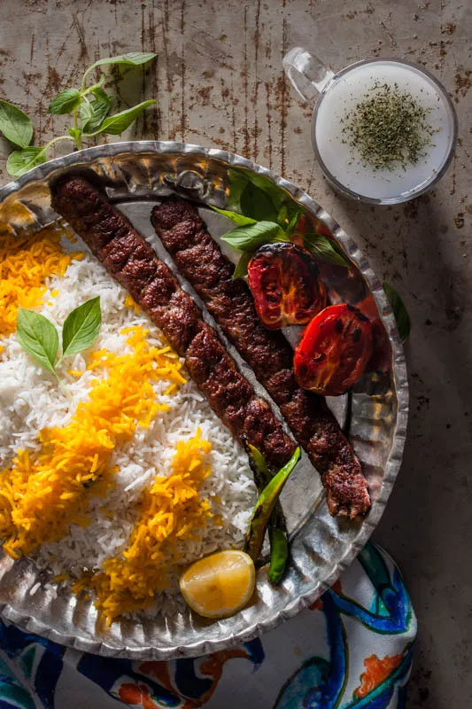Gegrillter Kebab Koobideh mit Basilikum, Zwiebeln und Doogh in einem Glas