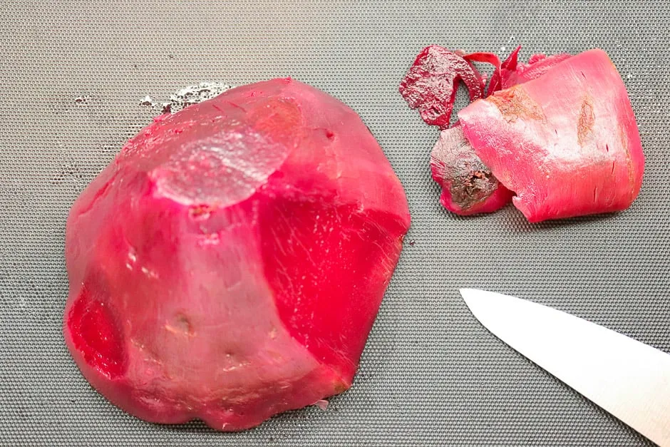 Gekochte rote Bete unter kaltem Wasser schälen, ein wichtiger Schritt für den Rote Rüben Salat