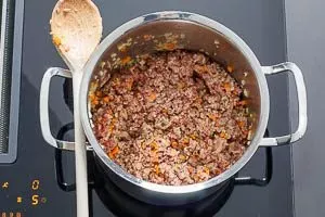 Gemischtes Hackfleisch zum Soffritto und Pancetta in den Topf geben