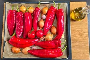 Gemüse für Ajvar: Paprika, Tomaten, Zwiebeln und Knoblauch auf einem Backblech, bereit zum Rösten