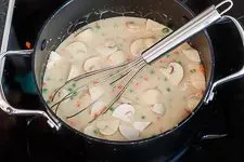 Gemüse und Sahne in die Frikasseesoße geben