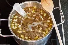 Gemüse und vorgekochte Linsen köcheln in Gemüsebrühe im Topf, ein herzhaftes Linsen Rezept entsteht